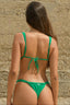 Woman wearing a green bikini against a stone wall.